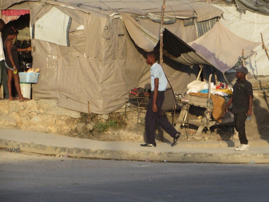 boy walking by houses where people are selling 