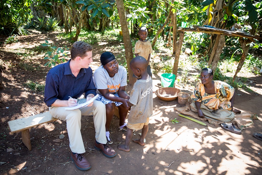 Jjajja is sitting in the corner during our first visit to Wabiduuku: Flavia and I are talking with Castol, Francis is standing by the tree, and Jjajja is sitting down (Photo credit: Tina LeAnn Photography)