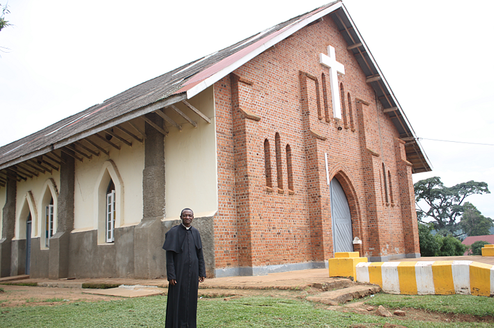 Fr. John Bosco in front of his local church, Our Lady Queen of Apostles in Nkokonjeru Fr. John Bosco in front of his local church, Our Lady Queen of Apostles in Nkokonjeru