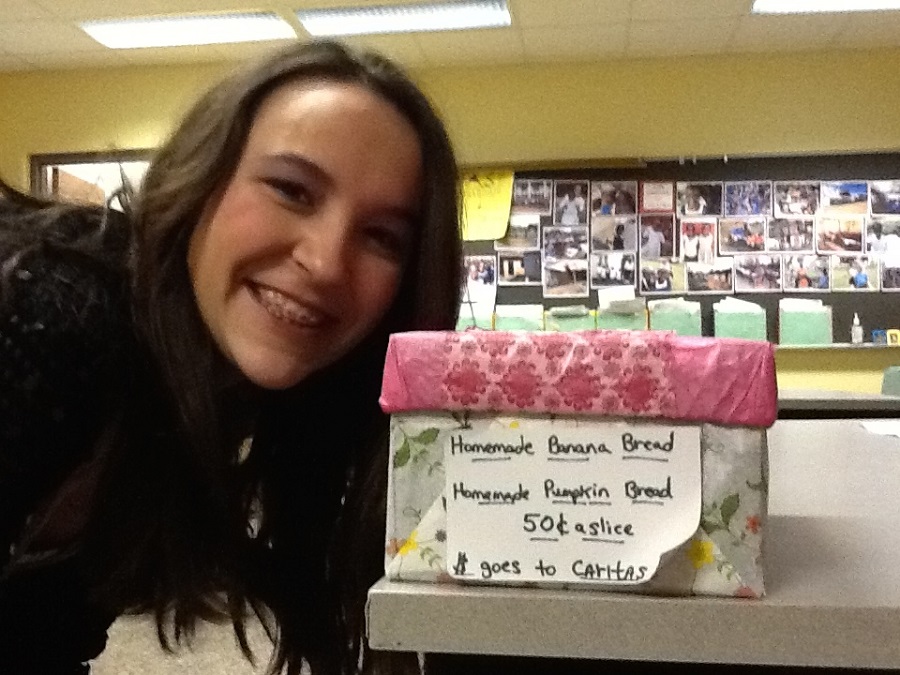 a girl posing by a sign offering baked goods for sale