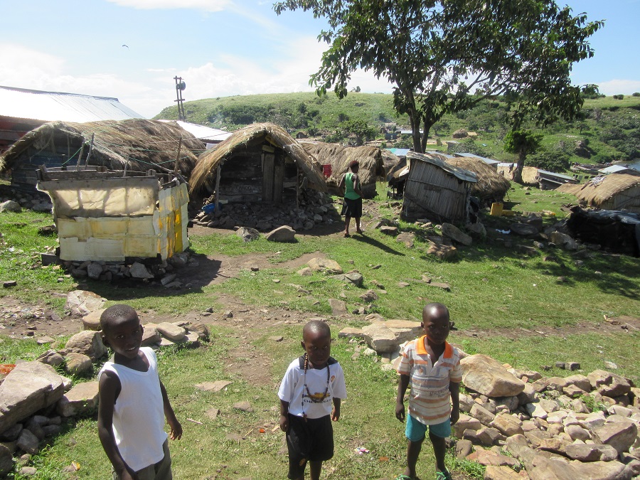 image of children standing in front of small reed-roofed homes