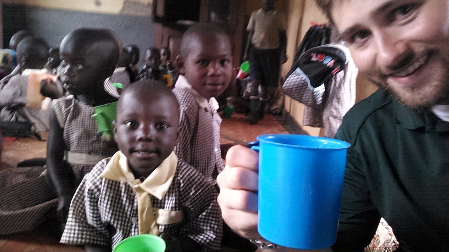 Kollin, CARITAS For Children Theology Content Writer, enjoys a serving of porridge with St. Anthony students.